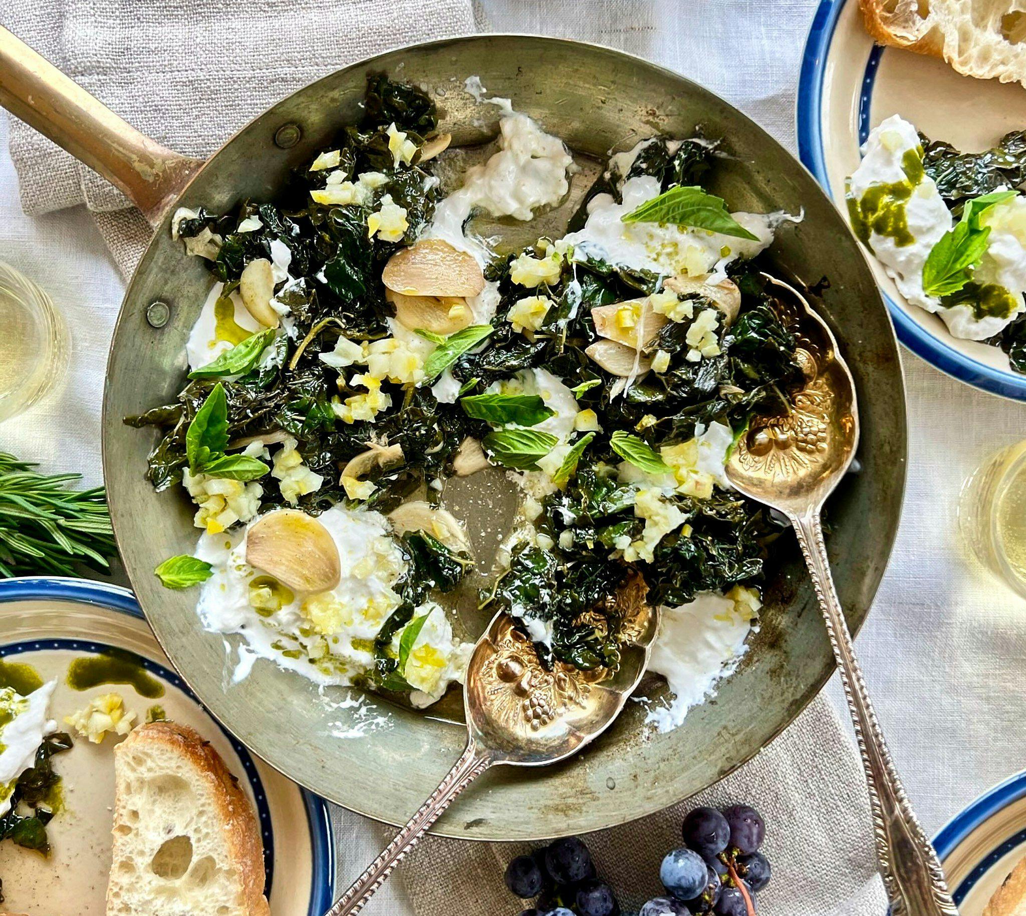 Braised Kale Stracciatella with lemon, garlic, & basil in a pan with golden spoons